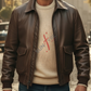 Man wearing a brown A2 bomber leather jacket over a beige sweater with a blurred street background