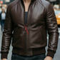 Man wearing a brown leather jacket with a red zipper on a city street.