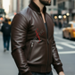 Man wearing a brown leather jacket with a brand logo on a city street