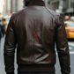 Man wearing a brown leather jacket with a visible brand logo on a city street.