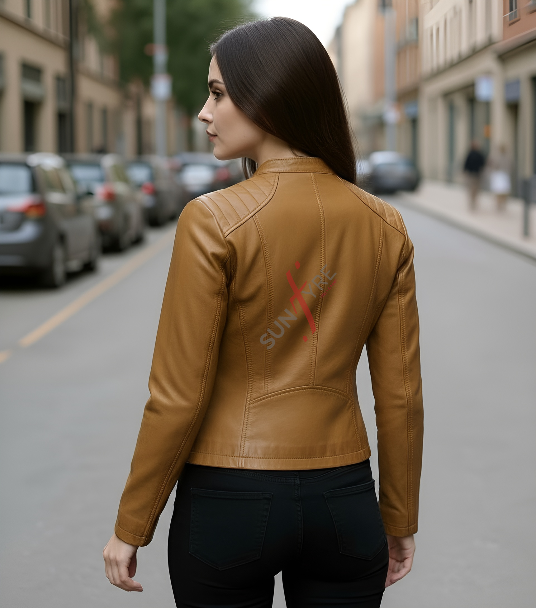 Woman wearing a tan leather jacket with a brand logo on a city street.