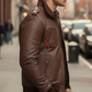 Man wearing a brown leather jacket with 'SUNRISE' branding on a city street.