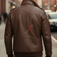 Man wearing a brown leather jacket with 'Sunfire' logo on the back, walking on a city street.