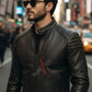 Man wearing a black leather jacket with a brand logo on a city street.