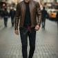 Man in a brown leather jacket walking on a city street
