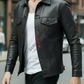 Person wearing a black leather jacket over a white shirt with red text, walking on a street.