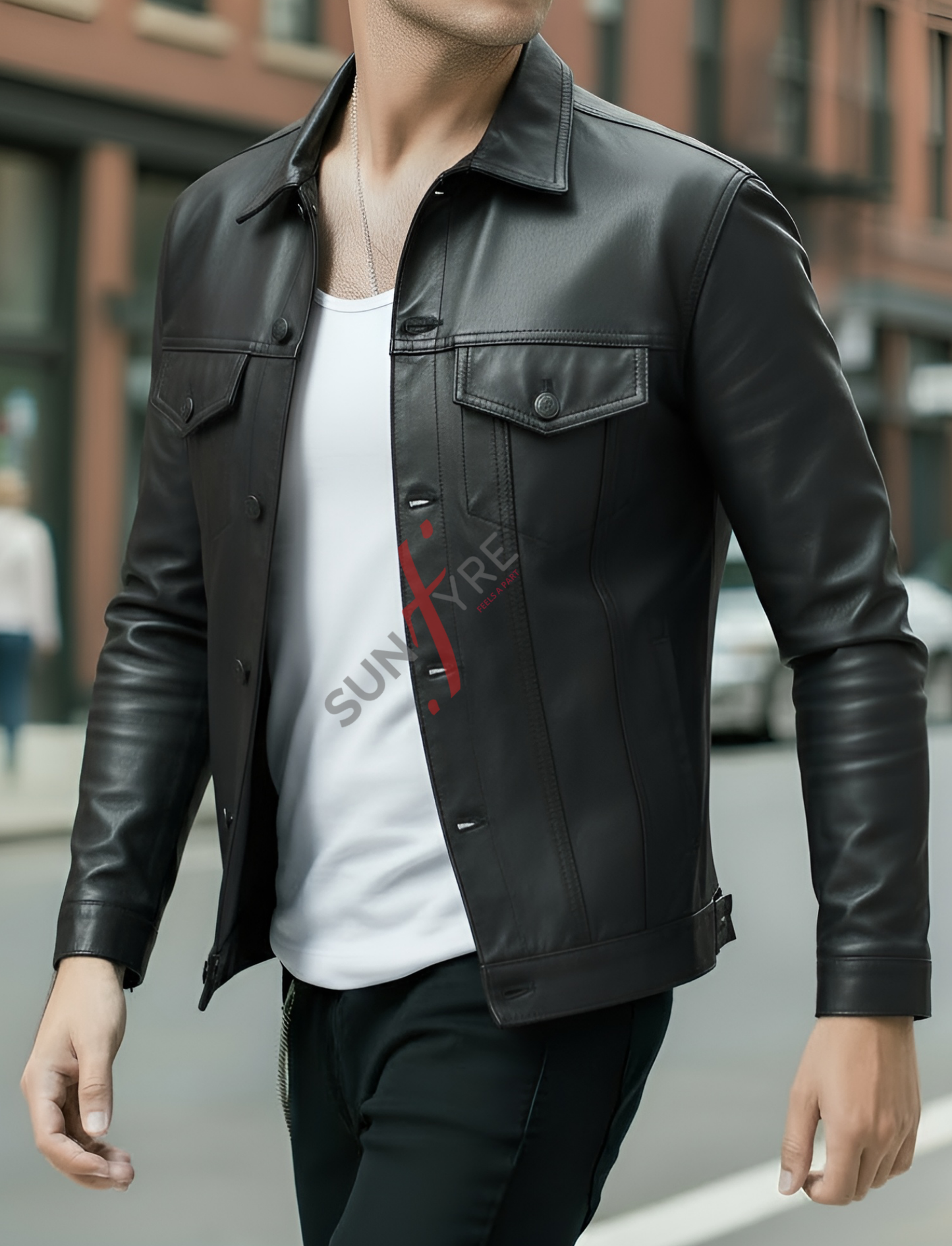 Person wearing a black leather jacket over a white shirt with red text, walking on a street.