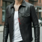 Man wearing a black leather jacket over a white shirt with red text, standing on a street.