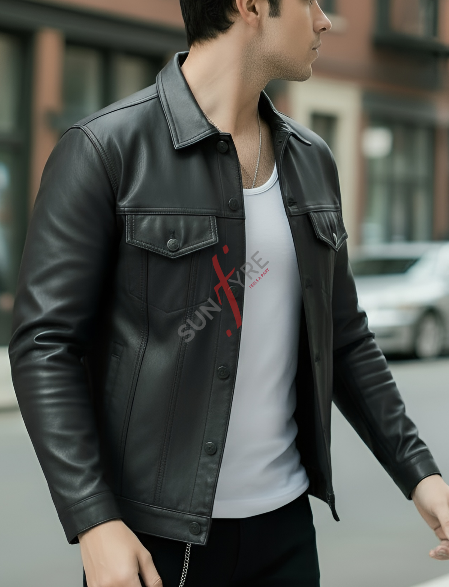 Man wearing a black leather jacket over a white shirt with a logo, standing on a street.