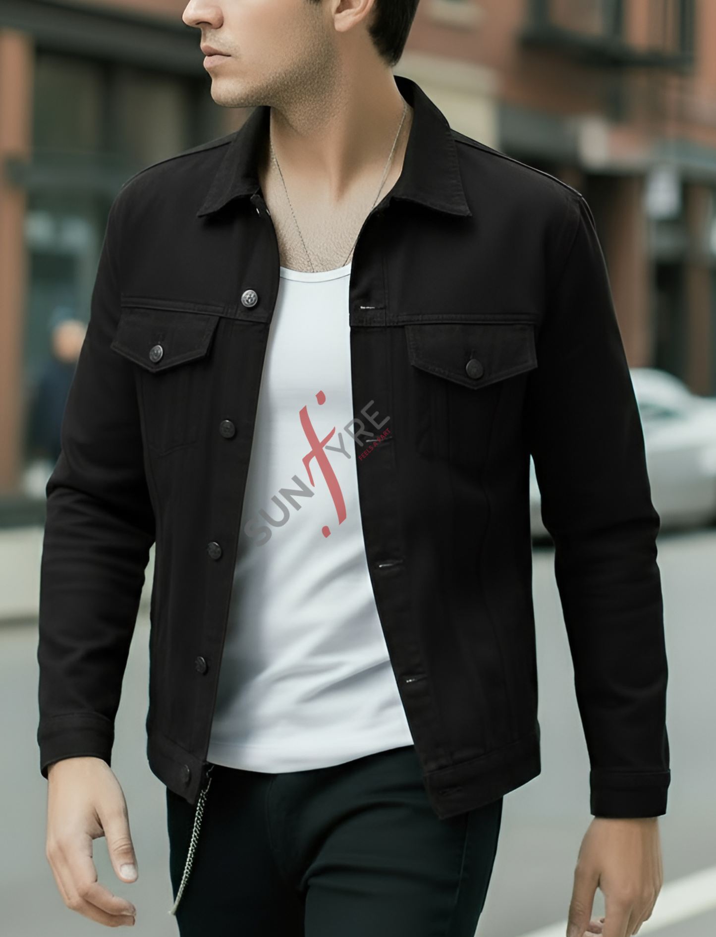 Man wearing a black jacket over a white t-shirt with red text on a blurred street background