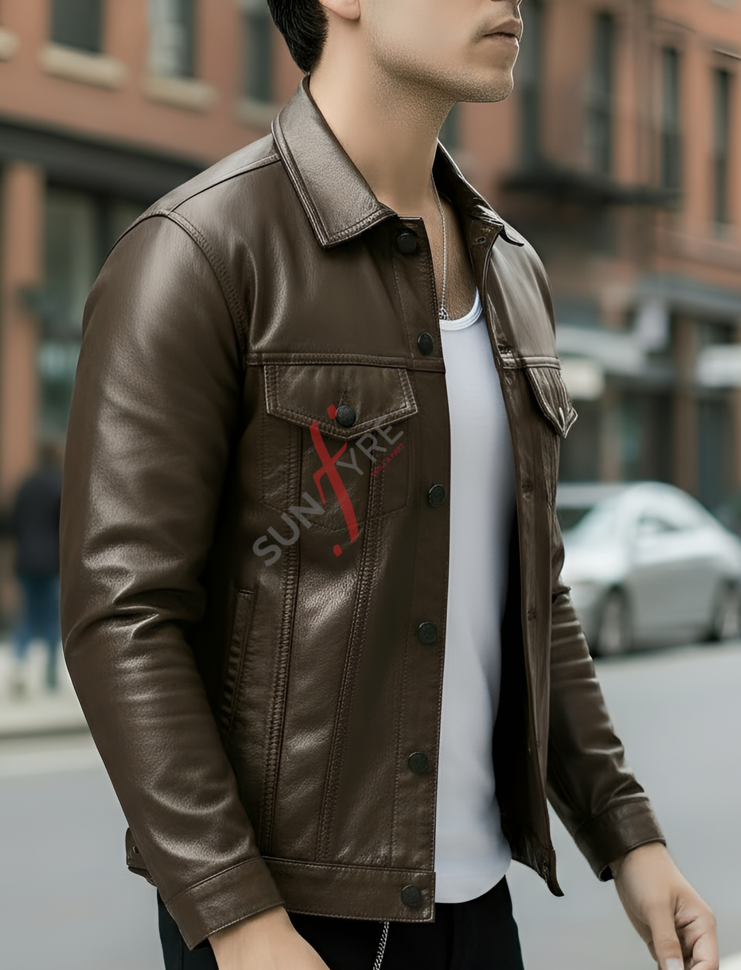 Person wearing a brown leather jacket with a visible brand logo on a city street.