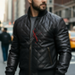 Man wearing a black leather jacket with a brand logo on a city street
