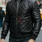 Man wearing a black quilted leather jacket with a brand logo in an urban setting
