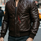 Man wearing a brown leather jacket with a brand logo on a city street.