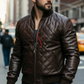 Man wearing a brown leather jacket with a brand logo in an urban setting