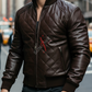 Man wearing a brown leather jacket with a brand logo on a city street.
