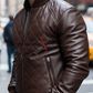 Man wearing a brown quilted leather jacket with a brand logo on a city street.