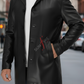 Person wearing a black leather jacket with a brand logo on a blurred street background