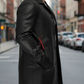 Person wearing a black leather coat with 'Suntory' logo on a city street.
