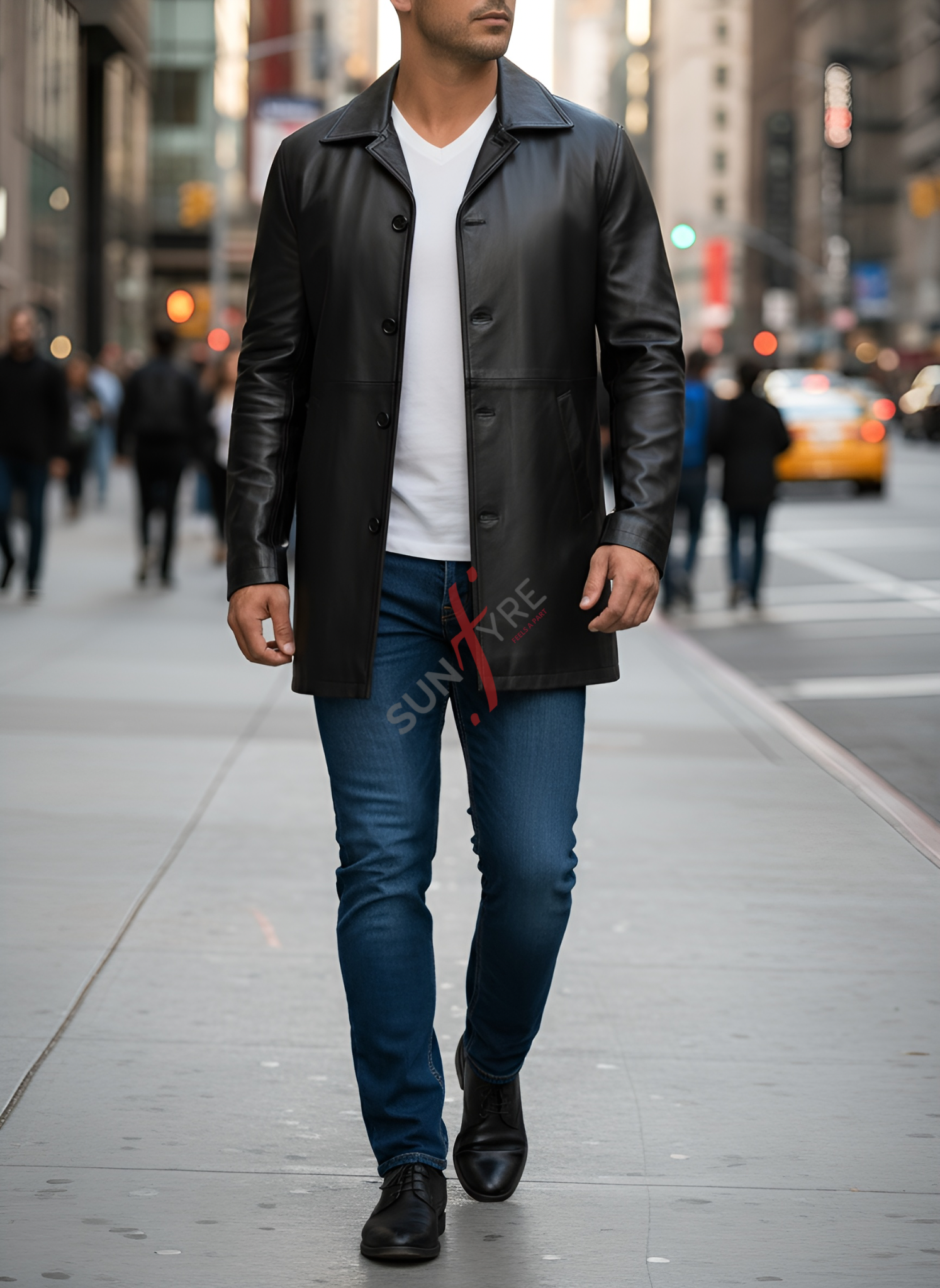 Man wearing a black leather coat and blue jeans walking on a city street.