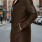 Man wearing a brown leather coat on a city street with 'Sunrye' branding.