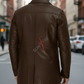 Man wearing a brown leather jacket with 'SUN' logo on a city street