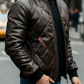 Man wearing a brown leather jacket with a brand logo on a city street.