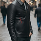 Man wearing a black leather jacket with a brand logo on a blurred street background