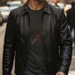 Man wearing a black leather jacket over a dark t-shirt with a logo, standing on a street.
