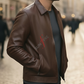 Man wearing a brown leather jacket with a logo on a blurred street background