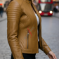 Woman wearing a cognac leather jacket on a city street with a blurred background