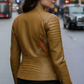 Woman wearing a cognac leather jacket with a brand logo on a city street.