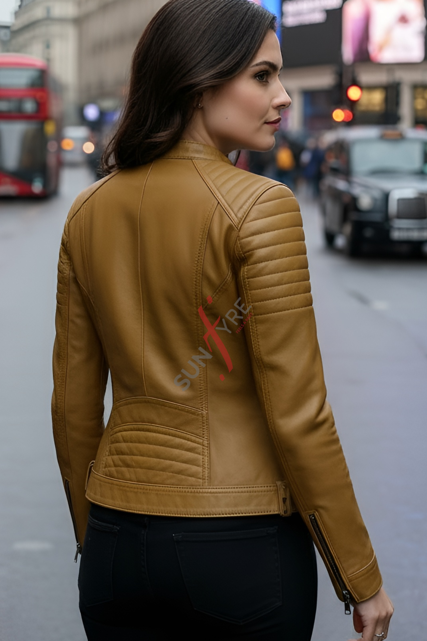 Woman wearing a cognac leather jacket with a brand logo on a city street.